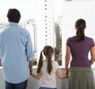 Expat family - parents and daughter - holding hands and looking from balcony