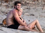 Snuggling in the sands: Liam Hemsworth wrapped fiance Miley Cyrus in his arms as the pair sat on the beach and watched the sun set during a romantic holiday in Costa Rica
